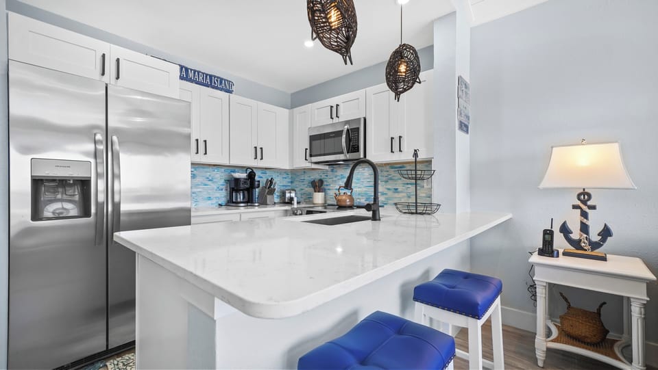 Bright coastal kitchen with quartz island, stainless steel, and bar seating