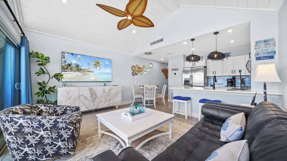 Bright coastal living space with vaulted ceilings and open kitchen bar