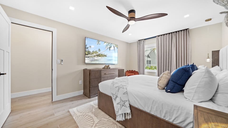 Bright coastal bedroom with king bed, TV, and serene modern style