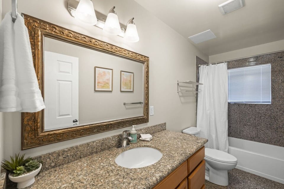 Full bathroom with a bathtub and shower combination, vanity, towels, and essential toiletries.