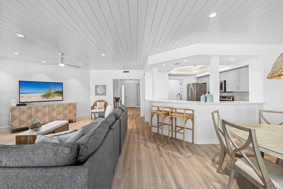 Wood dining table and a couch share the living area, a ceiling fan spinning above.
