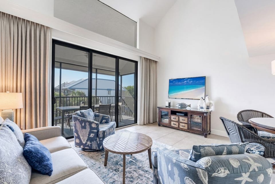 Coastal-inspired living area with comfortable seating, a TV, and access to a screened balcony.