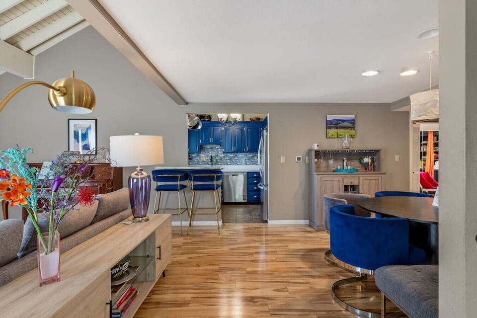 Bright open-concept kitchen with vibrant blue cabinetry, breakfast bar seating, hardwood floors, and seamless access to the dining and living areas—perfect for gathering with family and friends.