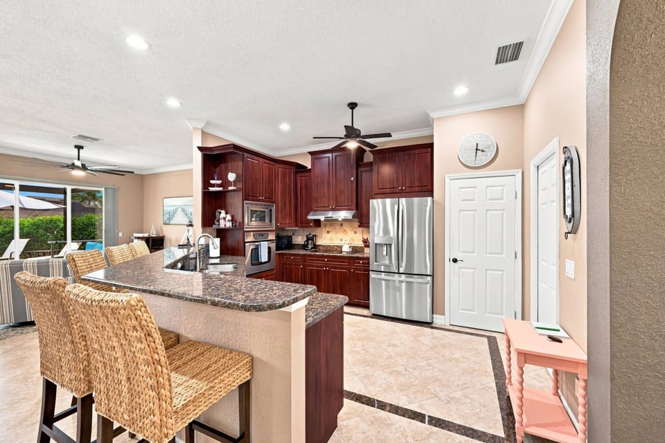 The spacious kitchen offers generous counter space, stainless steel appliances, and an oversized breakfast bar where everyone naturally gathers.
