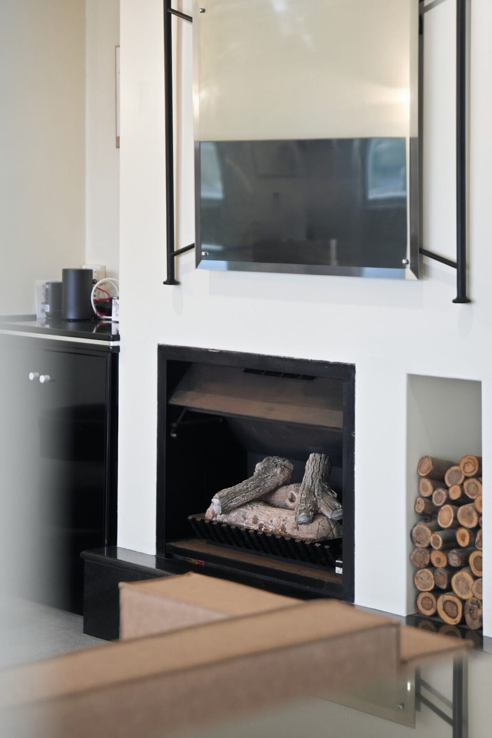 Cosy log-effect fireplace with mounted mirror above.