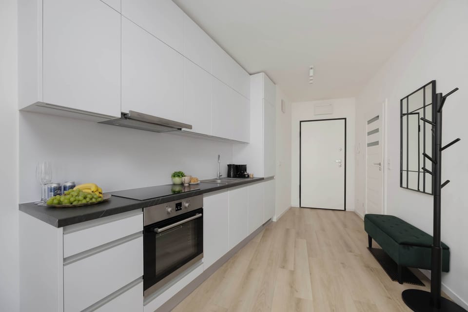 The entrance hallway view looks past the white kitchen counter toward the front door. A green upholstered bench and coat rack line the wall.