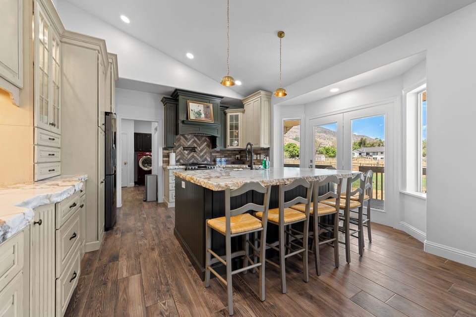The beautifully designed kitchen features a substantial central island, custom cabinetry, stone countertops, and seating for casual meals or conversation.