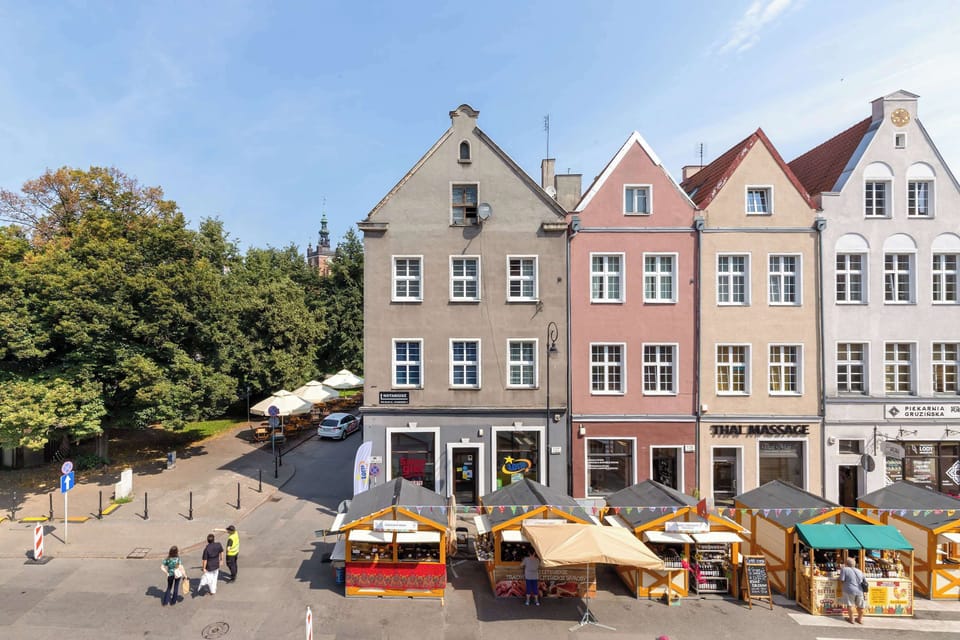 A beautiful view of colorful historic buildings surrounding a lively city square. Outdoor cafés and charming architecture create a welcoming atmosphere.