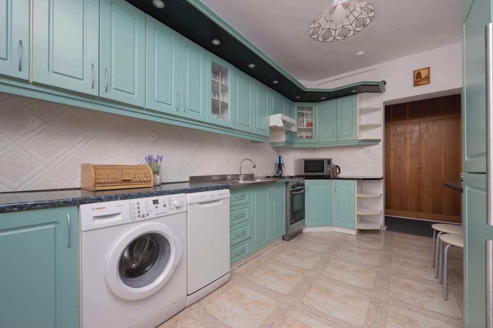 A bright kitchen features a washing machine, oven, and generous countertop space. The functional layout is ideal for preparing meals.