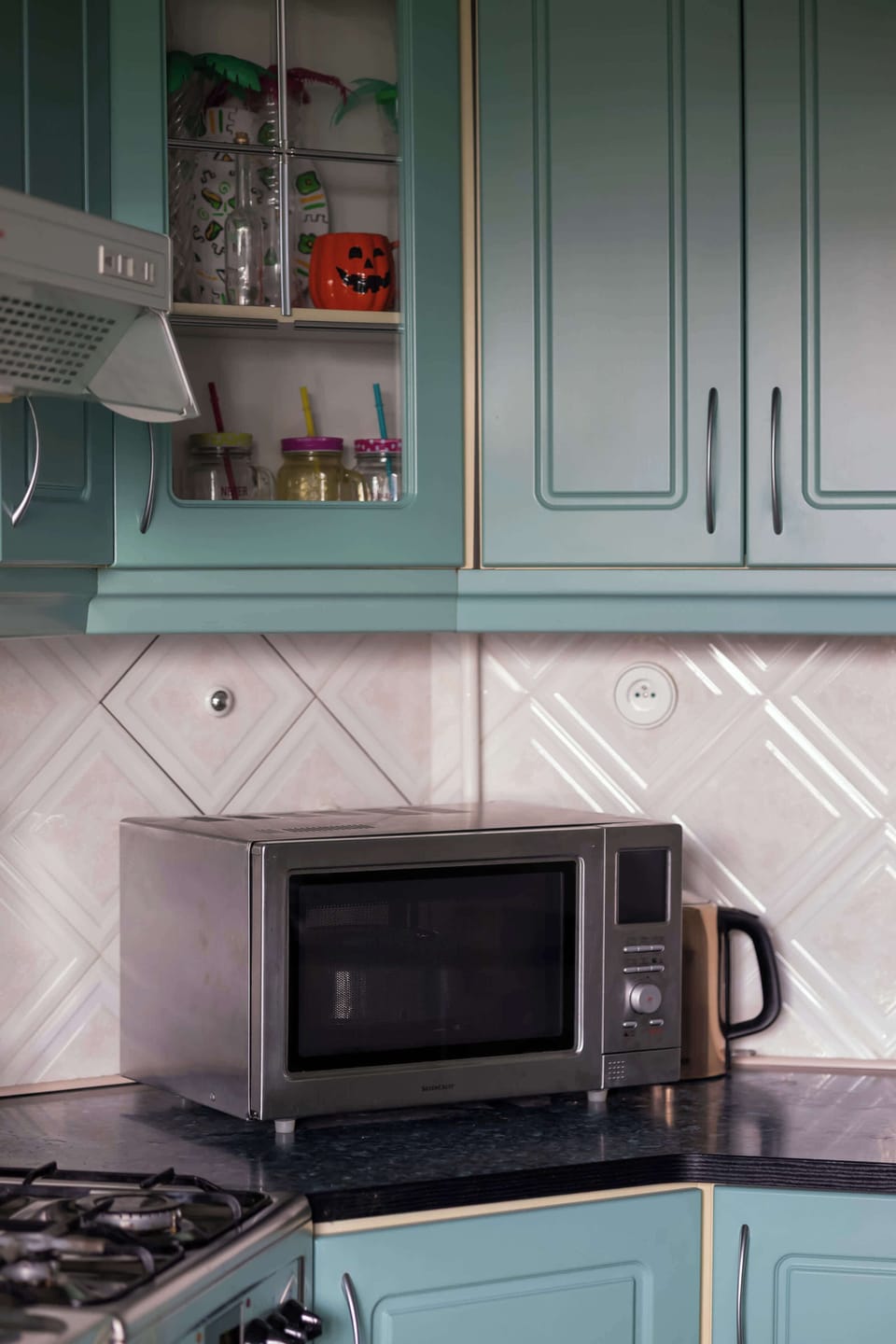 A section of the kitchen includes a microwave, cabinets, and additional countertop space. The practical layout makes everyday cooking convenient.