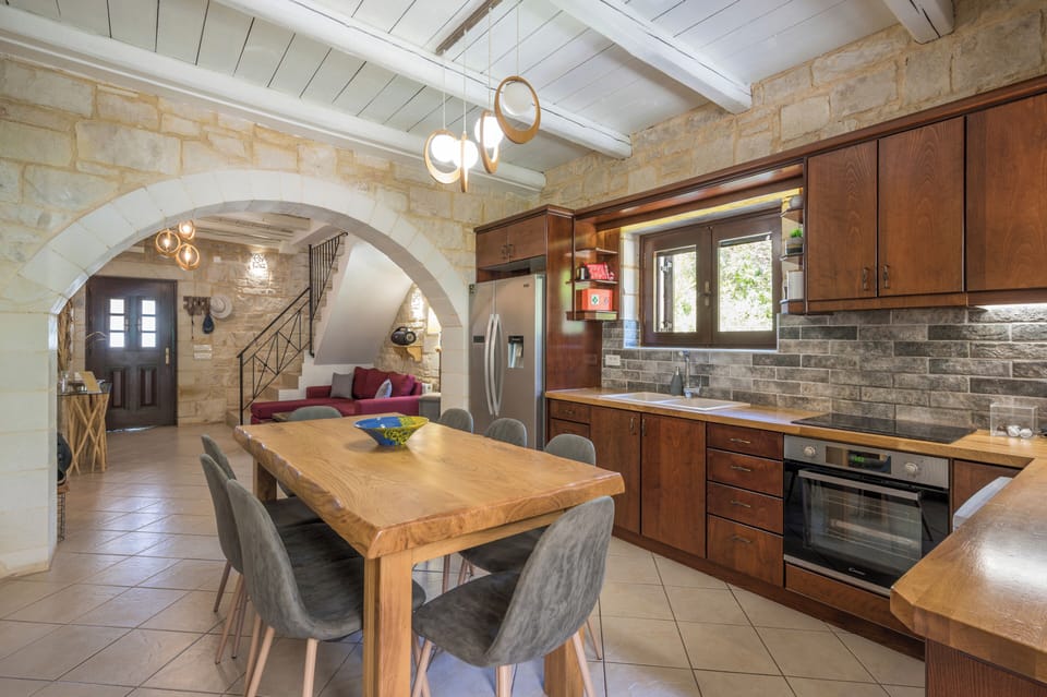 Charming stone-walled kitchen and dining area where rustic warmth meets modern comfort. Gather around the solid wood table, cook in the fully equipped space, and enjoy natural light streaming through the window.
