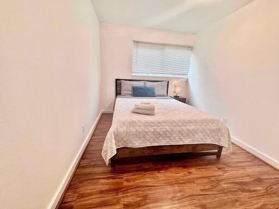 Bright, minimalist bedroom with warm floors and cozy queen bed