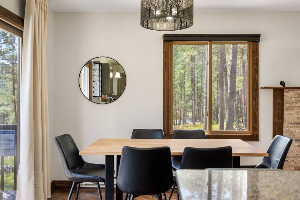 The dining area features a charming circular mirror and a window that brings in natural light, creating a bright and inviting space for shared meals and gatherings.