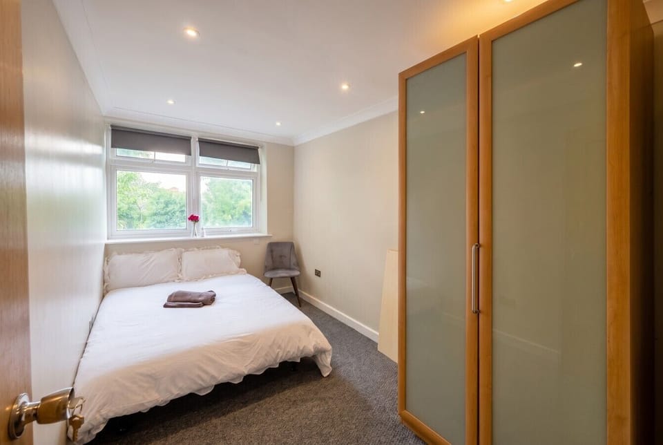 Restful double bedroom with soft light and leafy views to wake up to