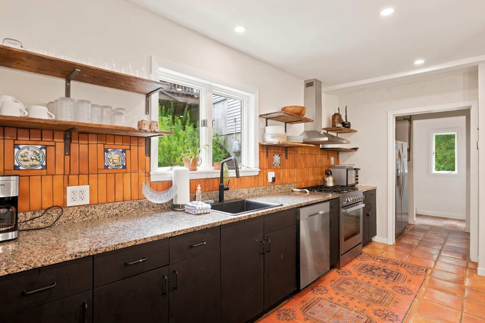 The kitchen comes well-equipped with a gas stove, dishwasher, and wood cabinetry, with a door out to the yard.
