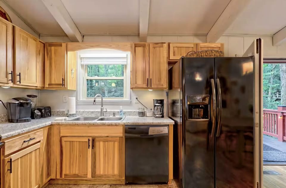 Warm wood kitchen with forest views, modern appliances, and deck access