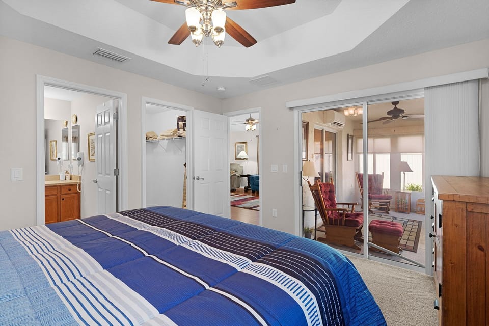 Settle into your airy bedroom with crisp linens and a ceiling fan overhead. Glass doors open to a private patio, while the en-suite bath and charming details create a restful escape.