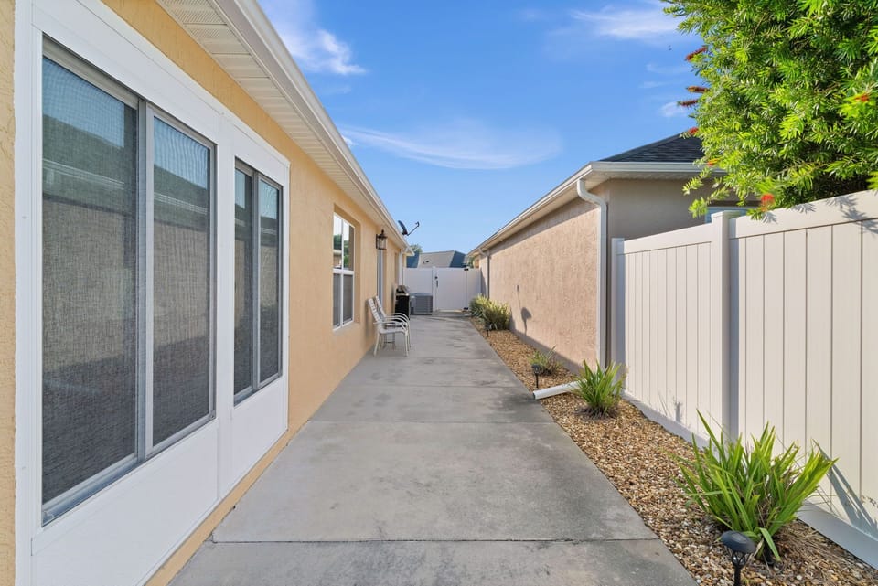 Exterior side walkway with desert-inspired landscaping and privacy fencing, offering convenient access to various areas of the property.