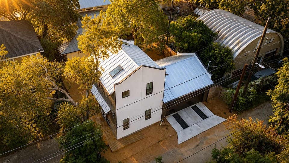 Aerial view: unit tucked in trees, private driveway and parking pad.
