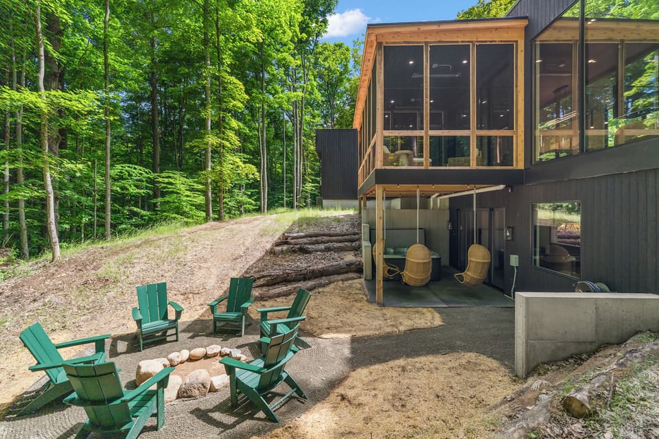 Modern forest retreat with fire pit, patio swings, and stunning windows