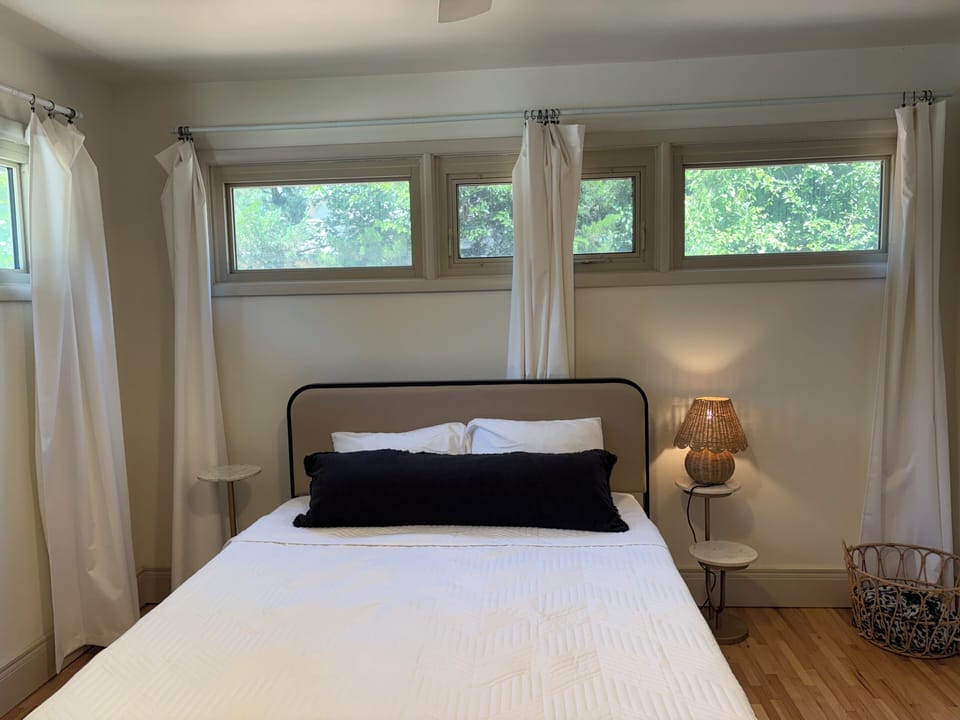 Bright minimalist bedroom with treetop views and cozy ambient lighting