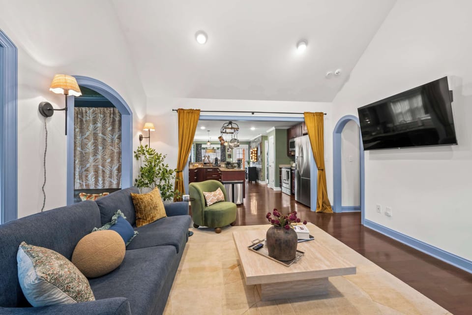 Vaulted ceilings, smart TV, and seating for a real group: two sofas, a velvet swivel chair, and a leather bench, wrapped in art and color at every turn.