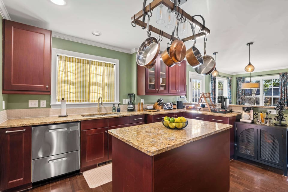 The chef's kitchen means it: hanging copper cookware, granite island, double-drawer dishwasher, and a fruit bowl that gets restocked. Cook like you're home. You are.
