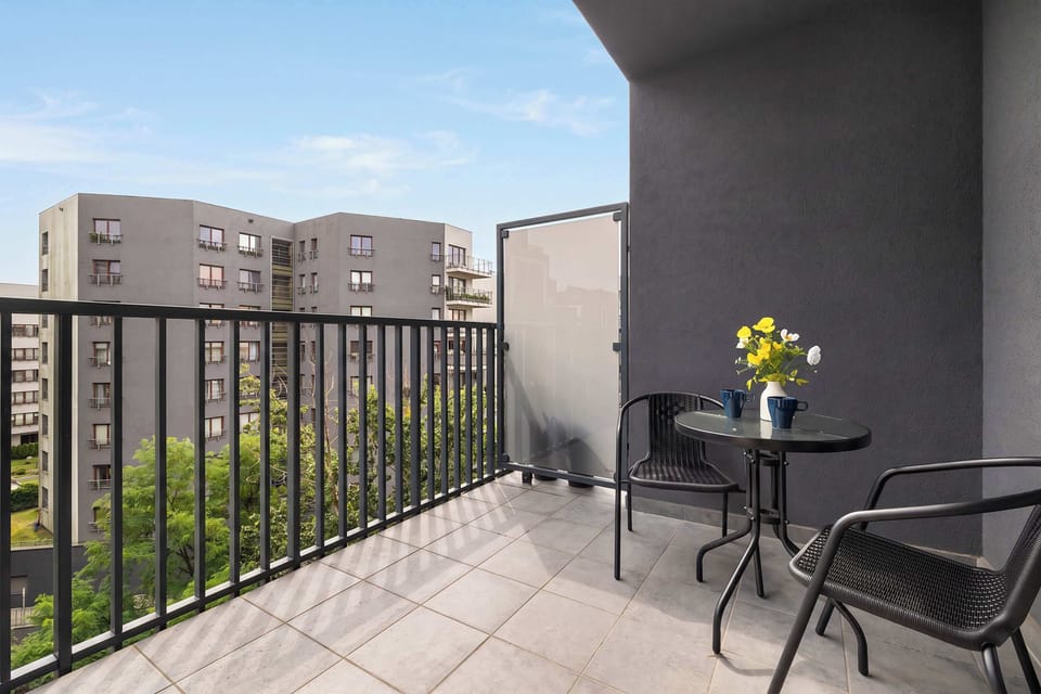 Private balcony with outdoor chairs and a small table overlooking the surrounding buildings.