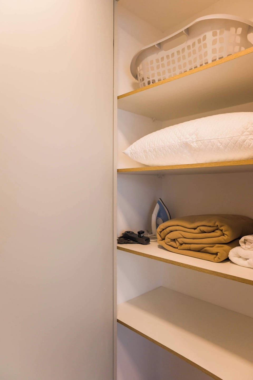 Conveniently organized closet with essentials like an iron and fresh linens for your stay.