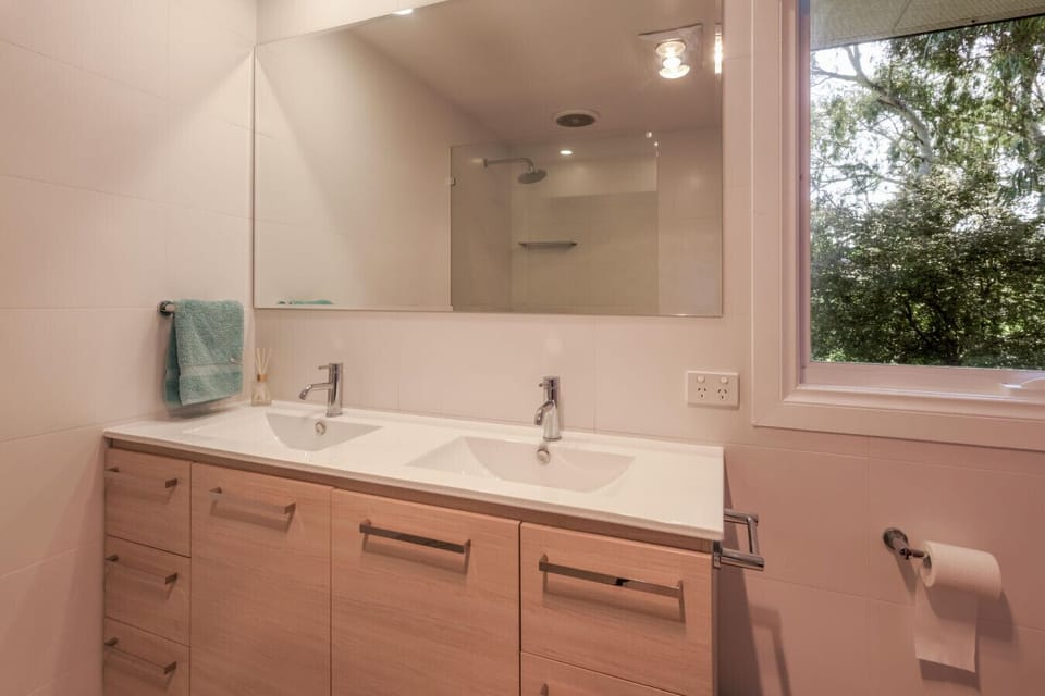 Recently renovated bathroom featuring a double vanity and walk-in rainfall shower