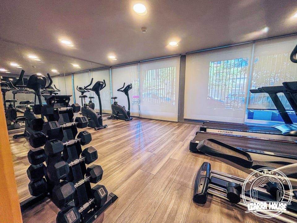 Bright on-site gym with cardio machines, weights, and mirrored walls