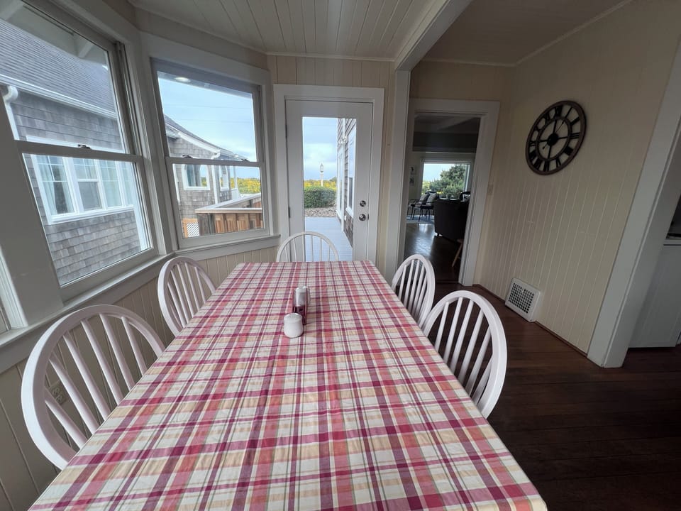 This charming entrance welcomes you with classic coastal cottage details—white paneling, decorative shutters, and a cheerful plaid awning overhead. Bright natural light streams in as you step through the door to your lakeside retreat.