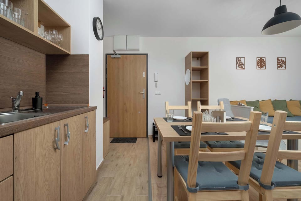 The dining area is well-lit and welcoming, perfectly arranged for a shared meal. The open layout connects smoothly to the hallway and the rest of the apartment.