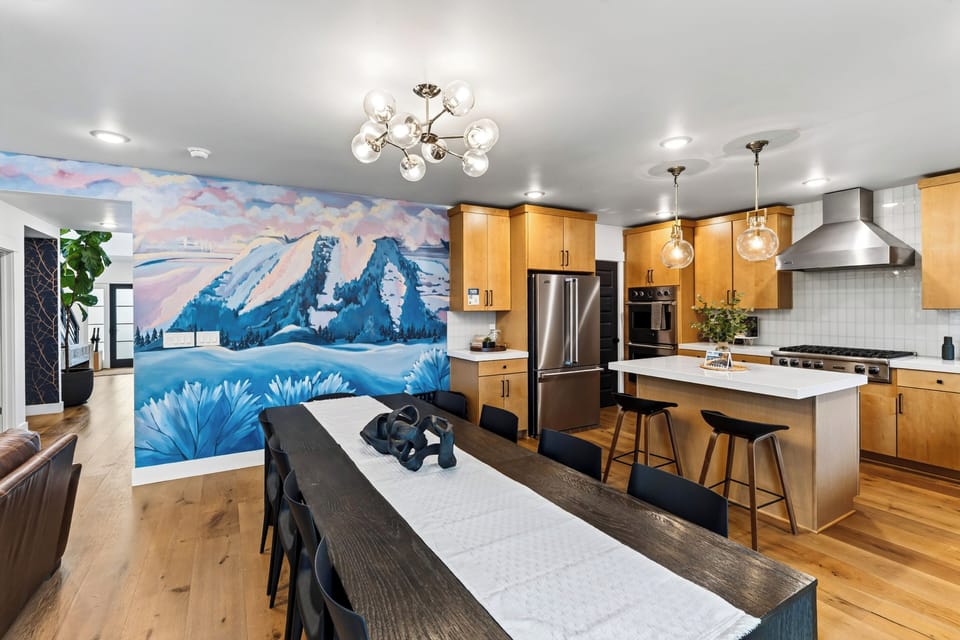 Dining area featuring a long table and striking blue mountain mural.
