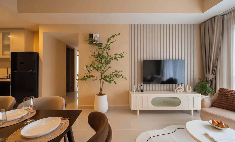 Spacious open-plan layout with smart TV, large plant, and soft lighting. The living room connects smoothly to the dining area, hallway, and kitchen. Perfect for relaxing, entertaining, or enjoying a cozy night in with seamless group flow.