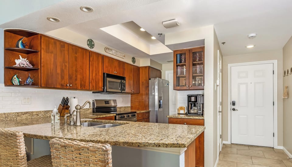 Well-equipped vacation rental kitchen featuring granite counters, abundant cabinetry, and breakfast bar seating