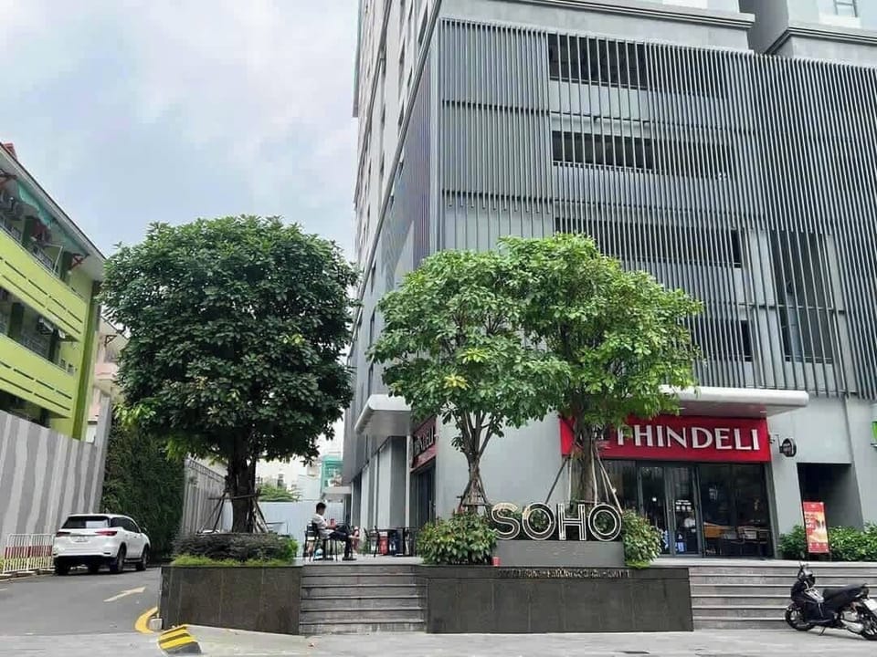 Street view of Soho Residence. Grab/taxi drop-off is via the driveway on the left. Entrance is on the right. A café sits outside next to Phin Deli. A spa is located beside the entrance inside.