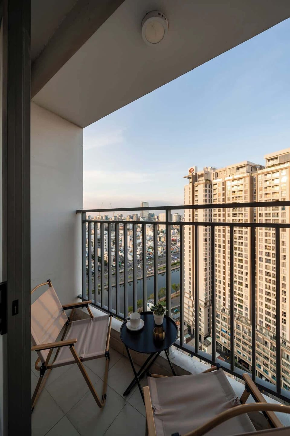 Main balcony area with seat and table with stunning lake and city view.