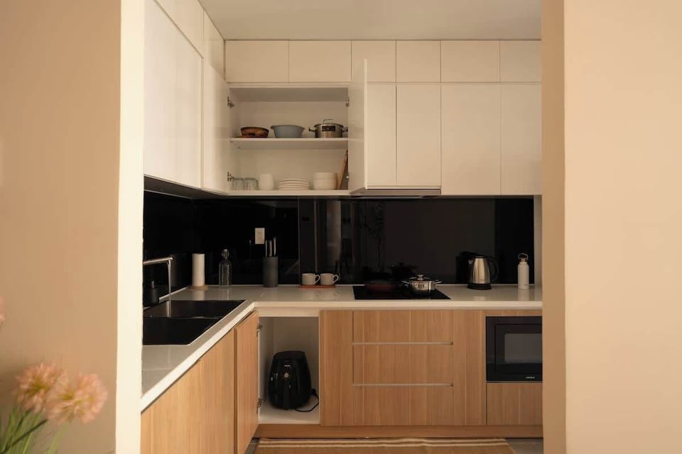 Large kitchen full of your essentials including: electric stove, air fryer, microwave, kitchen knife set, coffee mugs, pots, pans, cups, plates and a kettle.