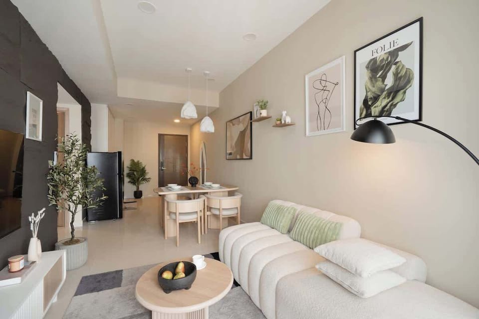 Minimalist & cozy design with a soft boucle sofa for 3, smart TV, dining area for 4, and a full kitchen just behind, perfect for lounging or enjoying a casual meal with friends.