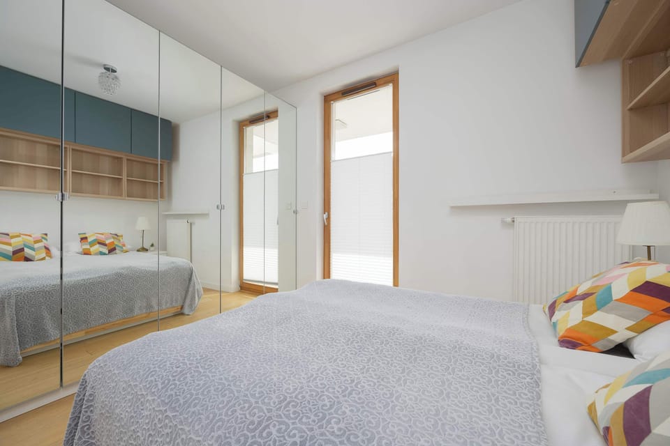 Another bedroom view highlighting a large window, built-in storage above the bed, and soft neutral décor.