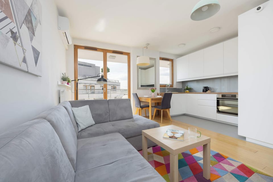 A cozy seating area with a gray sectional sofa positioned beside large windows that fill the room with daylight.