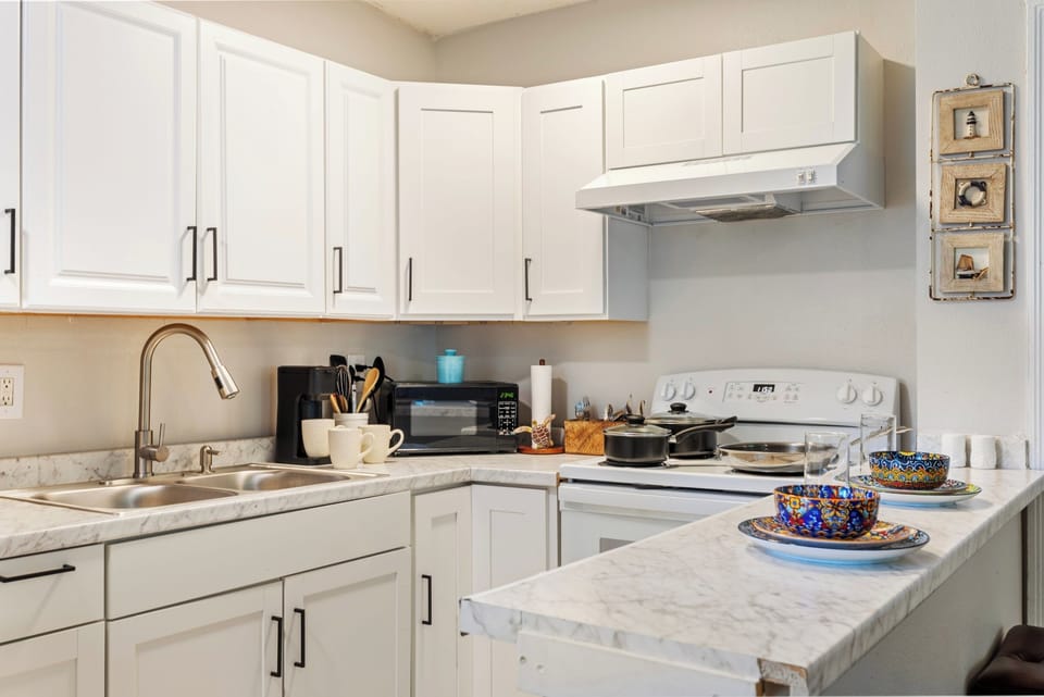 Whip up a fresh catch in this bright, fully stocked kitchen, with pots, coffee maker, and colorful dishware ready to go.