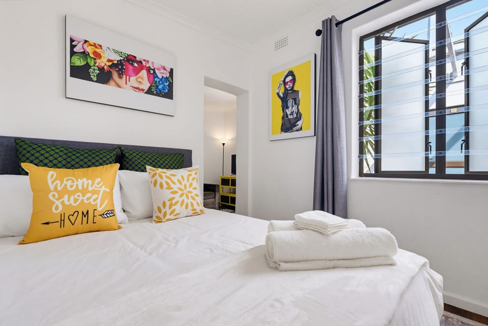 Bright, stylish bedroom with crisp linens, bold art, and natural light