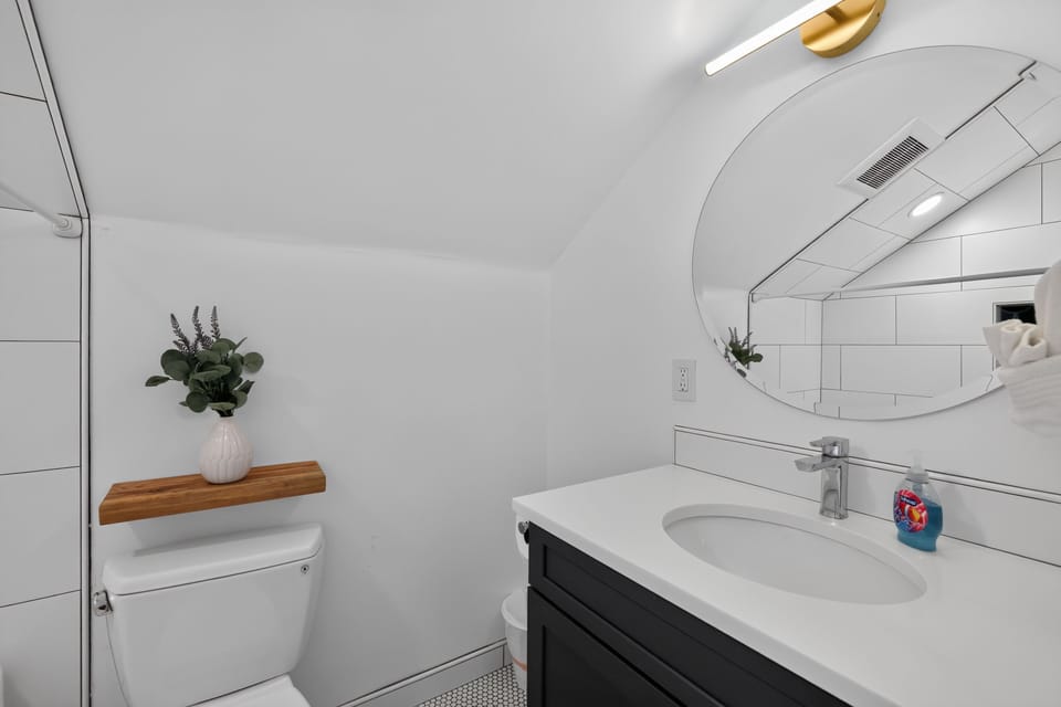 Bathroom featuring a dark vanity with a white countertop and a round mirror.