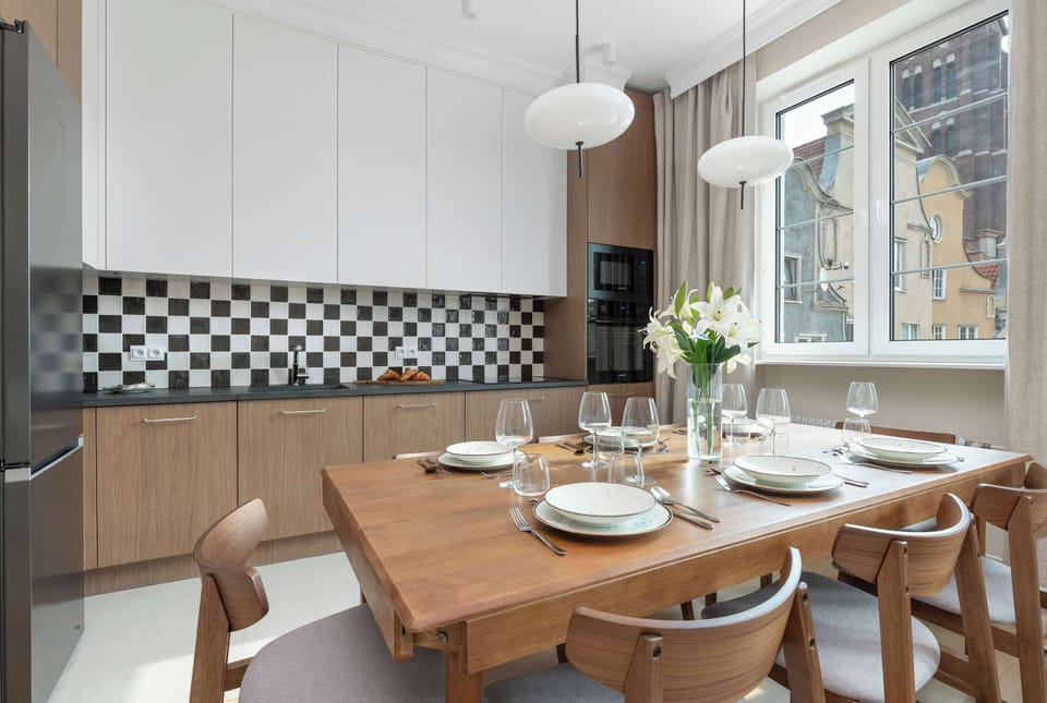 A modern kitchen with white cabinetry and integrated appliances arranged in a compact layout. The bright finishes keep the room feeling spacious.