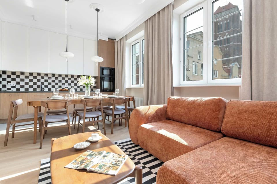A warm living room with a brown leather sofa, exposed brick walls, and a TV. The combination of rustic and modern elements creates a unique atmosphere.