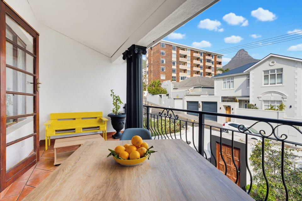 Covered balcony with outdoor dining, street views, and a mountain backdrop