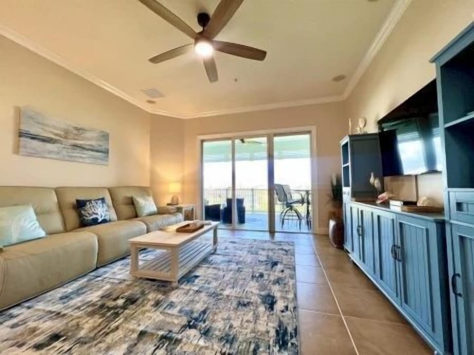 Living area with a tan sofa, blue rug, and sliding glass doors opening to the ocean balcony
