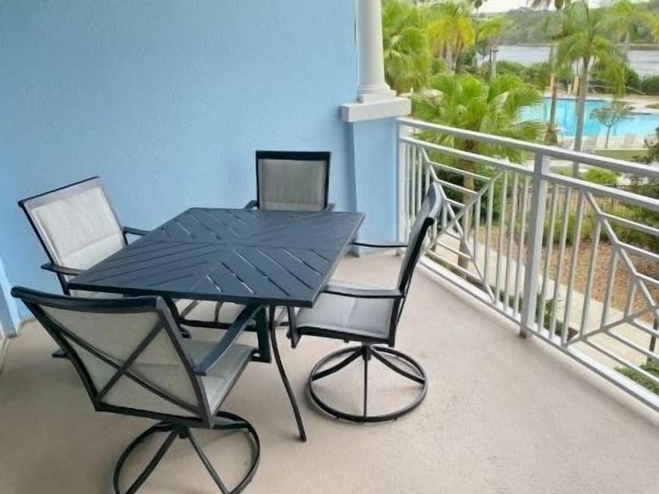 Private balcony with seating and open views to the pool and palm-lined waterway beyond